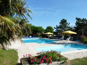 a swimming pool with flowers and umbrellas at Gîtes Chez Belliveau in Meursac