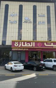 dos coches estacionados frente a un edificio en فخامة الديار للشقق المخدومة Fakhamat Aldyar For Serviced Apartments, en Taif