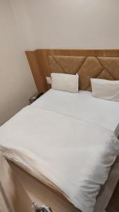 a large white bed with white sheets and pillows at HOTEL GANGARANI in Haridwār