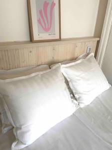 a bed with white pillows and a picture on the wall at Cozy studio in the heart of Kallio next to metro in Helsinki