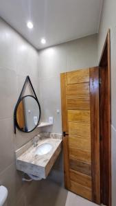 a bathroom with a sink and a mirror and a wooden door at Casa PraiAmar Atalaia in Salinópolis