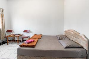 a bed in a room with two chairs and a table at Abang Hotel Ciwidey in Ciwidey