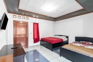 a room with two beds and a desk and a table at Abang Hotel Ciwidey in Ciwidey +28 photos