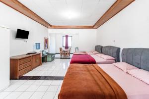 a room with three beds and a desk at Abang Hotel Ciwidey in Ciwidey