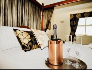 Una botella de vino en un cubo en una cama con vasos en Rusland Pool Hotel en Bouth