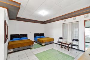 a room with two beds and a table and chairs at Abang Hotel Ciwidey in Bandung