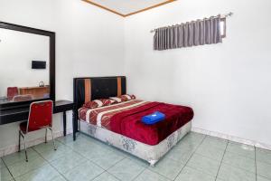 a bedroom with a bed and a desk and a mirror at Abang Hotel Ciwidey in Ciwidey