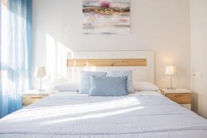 a bedroom with a large white bed with blue pillows at Cubo's Apartamento Perla del Sol 3I in Torremolinos
