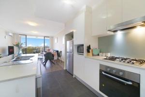 a kitchen with white countertops and a dining room at Shyline Views - Beautiful Condo In Wolli Creek in Sydney
