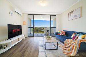 ein Wohnzimmer mit einem blauen Sofa und einem Tisch in der Unterkunft Shyline Views - Beautiful Condo In Wolli Creek in Sydney