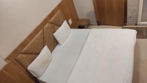 Bett mit weißer Bettwäsche und Kissen in einem Zimmer in der Unterkunft HOTEL GANGARANI in Haridwar