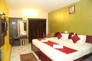 een hotelkamer met een groot bed met rode kussens bij LA FLORA SKT, YERCAUD in Yercaud