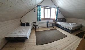 an attic room with two beds and a window at Piligrimo sodyba in Kadarės