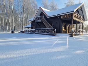Cabaña de madera en la nieve con suelo cubierto de nieve en Piligrimo sodyba, en Kadarės