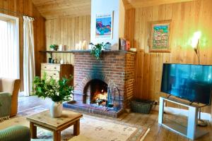 a living room with a brick fireplace and a tv at 3 Bed Cabin in the Woods in Barham