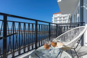 a balcony with a table and two glasses of beer at Bulwar Zachodzącego Słońca Apartament z Widokiem na Morze by Noclegi Renters in Darłówko