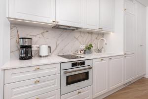 a white kitchen with white cabinets and a stove at Bulwar Zachodzącego Słońca Apartament z Widokiem na Morze by Noclegi Renters in Darłówko