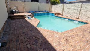 a swimming pool with a brick floor and blue water at Kabana Family Home and Guest House in Cape Town