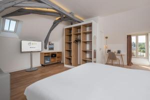 een kamer met een bed en een televisie en een tafel bij La Clef des Châteaux in Maslives