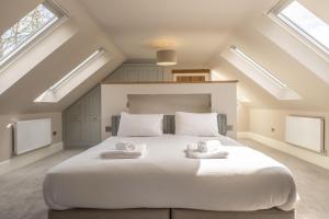 a bedroom with a large white bed with skylights at Wild Meadow Barn in Aylsham