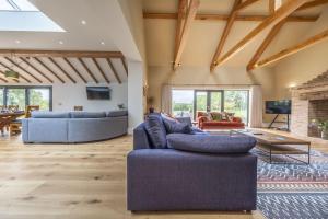 a living room with two blue couches and a table at Wild Meadow Barn in Aylsham