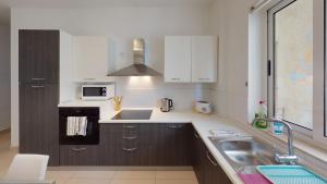 uma cozinha com um lavatório e um micro-ondas em St Julians - Balluta 2 bedroom apartment em St Julian's
