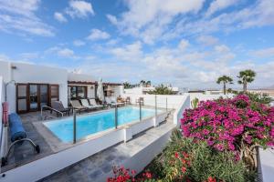 プラヤ・ブランカにあるVILLAS LANZAROTE LOS ALTOS by NEW LANZASUITES Villa SERENAのスイミングプールと花を備えたヴィラ