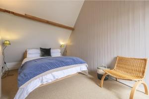 um quarto com uma cama e uma cadeira em Water Mill House em Burnham Market
