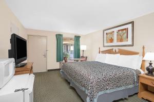 a hotel room with a bed and a flat screen tv at Days Inn by Wyndham Attalla in Attalla