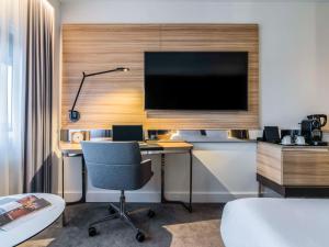 Zimmer mit Schreibtisch, Monitor und Stuhl in der Unterkunft Novotel Amsterdam City in Amsterdam