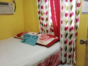 Dormitorio pequeño con cama con cortina de tulipanes en Jeremiah Homestay near Masasa Beach, en Batangas