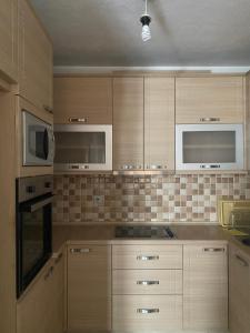 a kitchen with wooden cabinets and microwaves at Kosova in Kosovo Polje