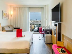 Habitación de hotel con cama y ventana grande en Novotel Barcelona City, en Barcelona