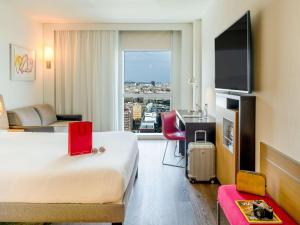 a hotel room with a bed and a large window at Novotel Barcelona City in Barcelona