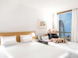 a hotel room with two beds with a teddy bear at Novotel Barcelona City in Barcelona