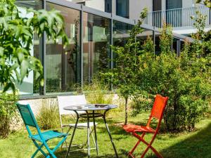 3 Stühle und ein Tisch vor einem Gebäude in der Unterkunft ibis Styles Paris Porte d'Orléans in Montrouge