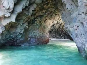 a cave with turquoise water in a rock wall at Jeremiah Homestay near Masasa Beach in Batangas City +6 photos