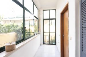 un couloir vide avec des fenêtres et une porte dans l'établissement Spacious 2 bedroom Apt with large living room Lisbon, à Lisbonne