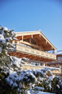 a large wooden building with a deck in the snow at Tennerhof Luxury Chalets in Kitzbühel
