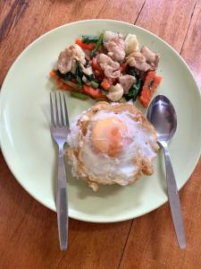 a white plate with an egg and vegetables on a table at kohkoodfarmstay in Ban Ao Yai