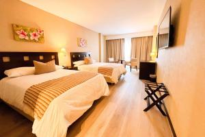 Cette chambre comprend deux lits et une télévision. dans l'établissement Howard Johnson Hotel & Resort Funes, à Funes