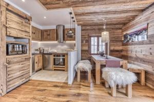 kuchnia z drewnianymi ścianami i stołem z dwoma stołkami w obiekcie Chalet 3 étoiles pour 4 pers avec vue imprenable sur la vallée de Chamonix w mieście Les Houches