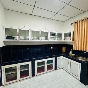 a kitchen with white cabinets and a black counter top at Jimmy House in Aluthgama