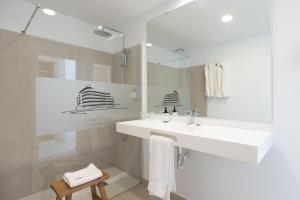 a white bathroom with a sink and a mirror at Hotel Médano in El Médano