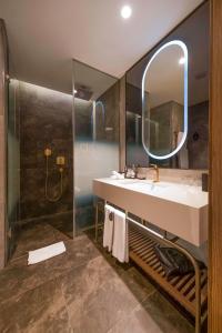a bathroom with a sink and a shower with a mirror at Radisson Collection Hotel, Vadistanbul in Istanbul