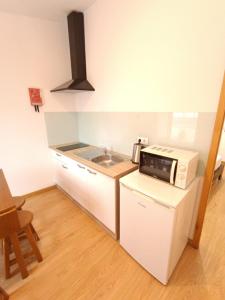 a small kitchen with a microwave and a sink at Invicta Porto Guest House in Porto