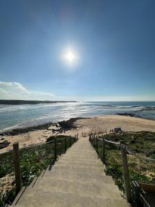 a stairway leading to a sandy beach with the ocean at Charm-In Center in Vila Nova de Milfontes