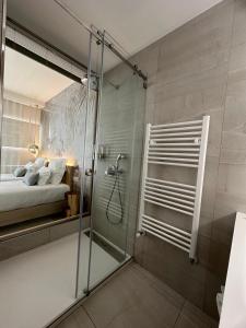a bathroom with a glass shower and a bed at Charm-In Center in Vila Nova de Milfontes