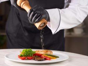 a chef is sprinkling sauce on a plate of food at Mövenpick Samarkand in Samarkand