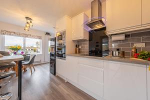 a kitchen with white cabinets and a dining table at The Saltings in Heacham